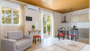 A modern hotel room with a sofa, two beds, a dining area, and a kitchen. - Standard Triple Room (Travliata)