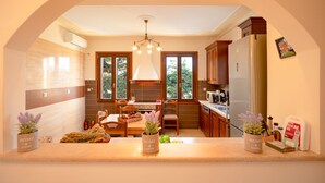A modern kitchen with a dining area, large windows, and a chandelier. - Villa Levanda in Matsoukata (Matsoukata)