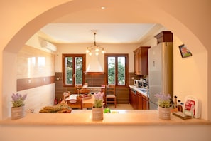A modern kitchen with a dining area, large windows, and a chandelier. - Villa Levanda in Matsoukata (Matsoukata)