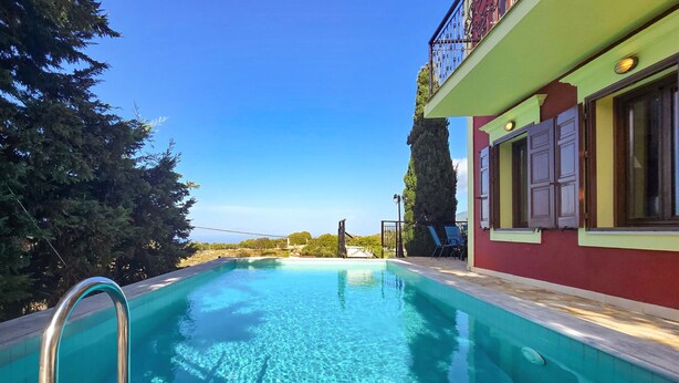 A clear blue swimming pool with a metal ladder, surrounded by trees and a building with a balcony. - Villa Levanda in Matsoukata (Matsoukata)