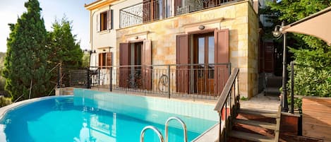 A two-story building with a swimming pool, a balcony with metal railings, and a wooden deck.