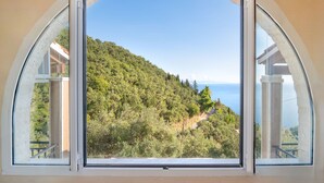 Una habitación con un amplio ventanal que ofrece vistas a una colina y al mar.