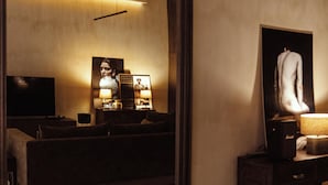 Ein modernes Schlafzimmer mit einem großen Spiegel, einem Bett, einem Fernseher und einer Lampe.