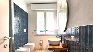 A modern bathroom with a herringbone wooden floor, two white bidets, a large mirror, and a wooden stool. - Apartment in a semi-detached house with independent entrance.-Rif. Casa Nina (San Vincenzo)