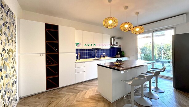 A modern kitchen with white cabinets, a central island with bar stools, a blue backsplash, and hanging pendant lights. - Apartment in a semi-detached house with independent entrance.-Rif. Casa Nina (San Vincenzo)