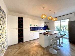 A modern kitchen with white cabinets, a central island with bar stools, a blue backsplash, and hanging pendant lights. - Apartment in a semi-detached house with independent entrance.-Rif. Casa Nina (San Vincenzo)