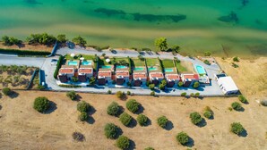 Eine Vogelperspektive eines Küstenhotels mit mehreren Gebäuden, einem Schwimmbad und einem Strand.