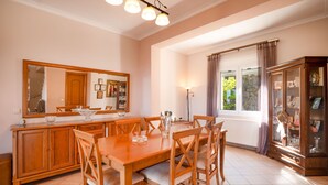 Una zona de dinar amb una taula i cadires de fusta, un moble amb portes de vidre i un mirall gran a la paret.