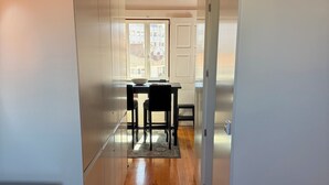 A narrow hallway with wooden flooring leading to a kitchen area with a dining table and chairs. - Charming apartment in the center of Porto! Lots of sunshine and a garage available. (Porto)