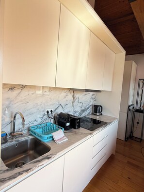 A kitchen with white cabinets, a marble countertop, a sink, a kettle, and a toaster. - Charming apartment in the center of Porto! Lots of sunshine and a garage available. (Porto)