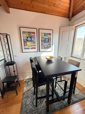A dining area with a dark wooden table, black chairs, and a rug. There are two framed posters on the wall. - Charming apartment in the center of Porto! Lots of sunshine and a garage available. (Porto)