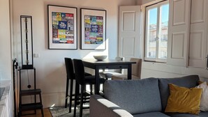 A living room with a grey sofa, a wooden ceiling, and two framed posters on the wall. - Charming apartment in the center of Porto! Lots of sunshine and a garage available. (Porto)