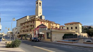 A historic building with a prominent clock tower, a covered entrance, and a street with a car parked in front. - 5 beds in central area with terrace-Rif. Campanile2 (San Vincenzo)