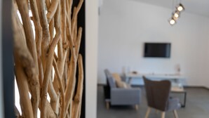 Un interior moderno con un revestimiento de madera decorativo, un sofá gris, un sillón marrón y un televisor de pantalla plana montado en la pared.