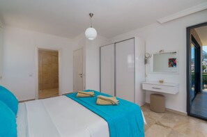 A bedroom with a bed, a bathroom with a mirror, and a view through a glass door. - Villa Vala in Kalkan (Kalkan)