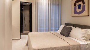 Een moderne hotelkamer met een groot bed, een douche en een groot raam met gordijnen.