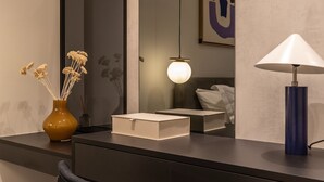 Een modern bureau met een vaas gedroogde bloemen, een lamp en een stoel.