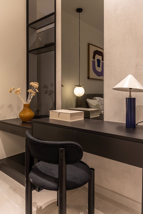 A modern desk with a vase of dried flowers, a lamp, and a chair.