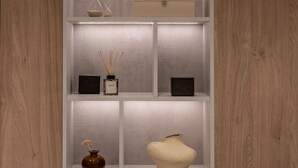 Un meuble d’étagères moderne et bien éclairé, agrémenté de divers objets décoratifs, notamment des vases et des boîtes, le tout sur un fond en bois.