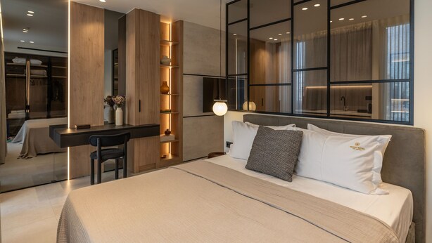 A modern hotel room with a bed, bedside table, and a desk area.