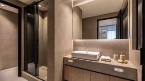 A modern bathroom with a glass shower enclosure, a large mirror, and a vanity with a sink and towel rack.