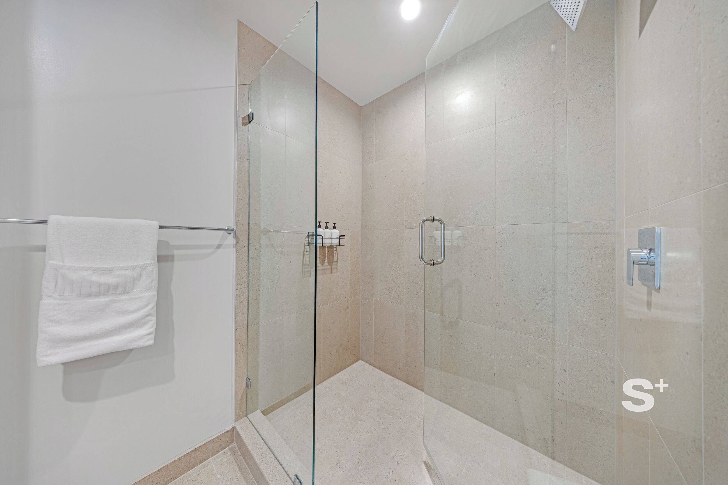 Un baño moderno con cabina de ducha de vidrio, un perchero y una puerta de vidrio.