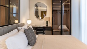 Ett modernt hotellrum med en stor säng, ett skrivbord, en stol, en spegel och en rymlig klädkammare.