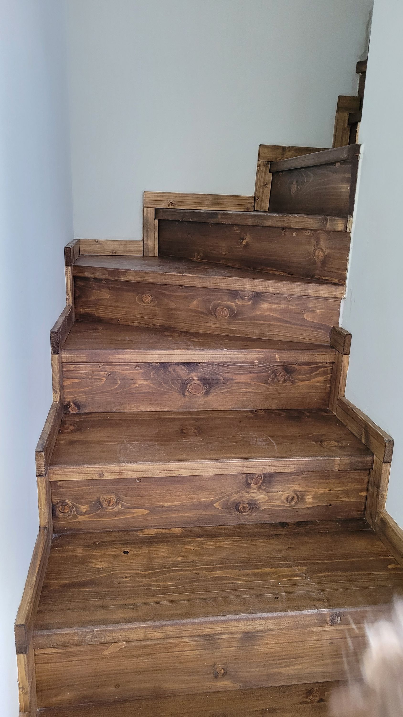 Een houten trap met een rustiek ontwerp, gemaakt van donkere houten planken.