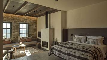Un dormitorio con pared de piedra, chimenea, cama y vistas al exterior.
