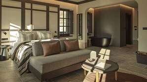 Et moderne soveværelse med en stor seng, en sofa, et sofabord og et badekar.