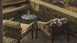 En terrasse med et bord og stole, med udsigt over et bjergrigt landskab.
