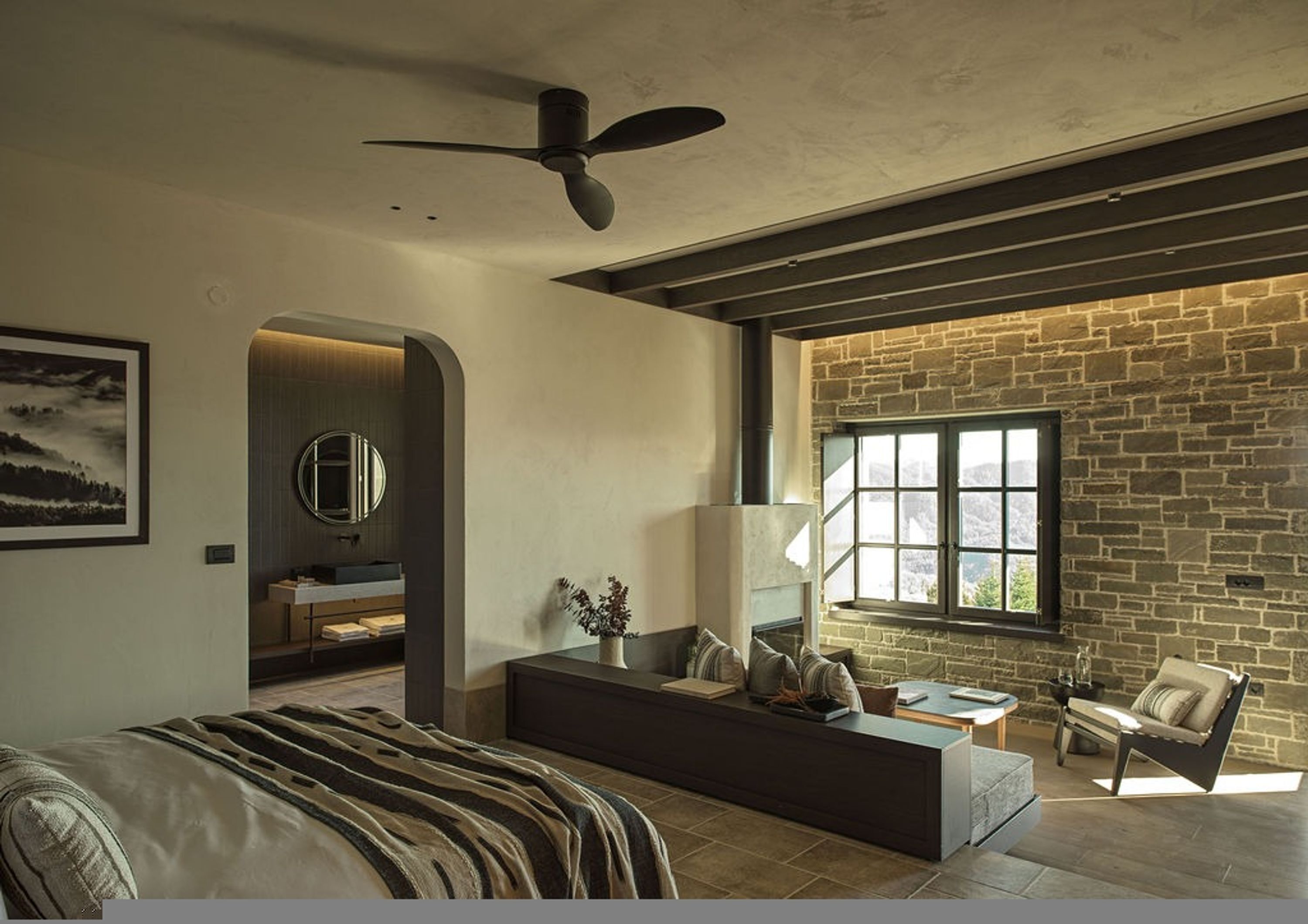 A modern living room with a large window, a fireplace, a sofa, and a ceiling fan.