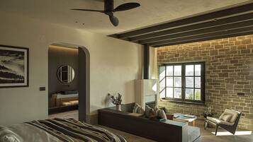A modern living room with a large window, a fireplace, a sofa, and a ceiling fan.