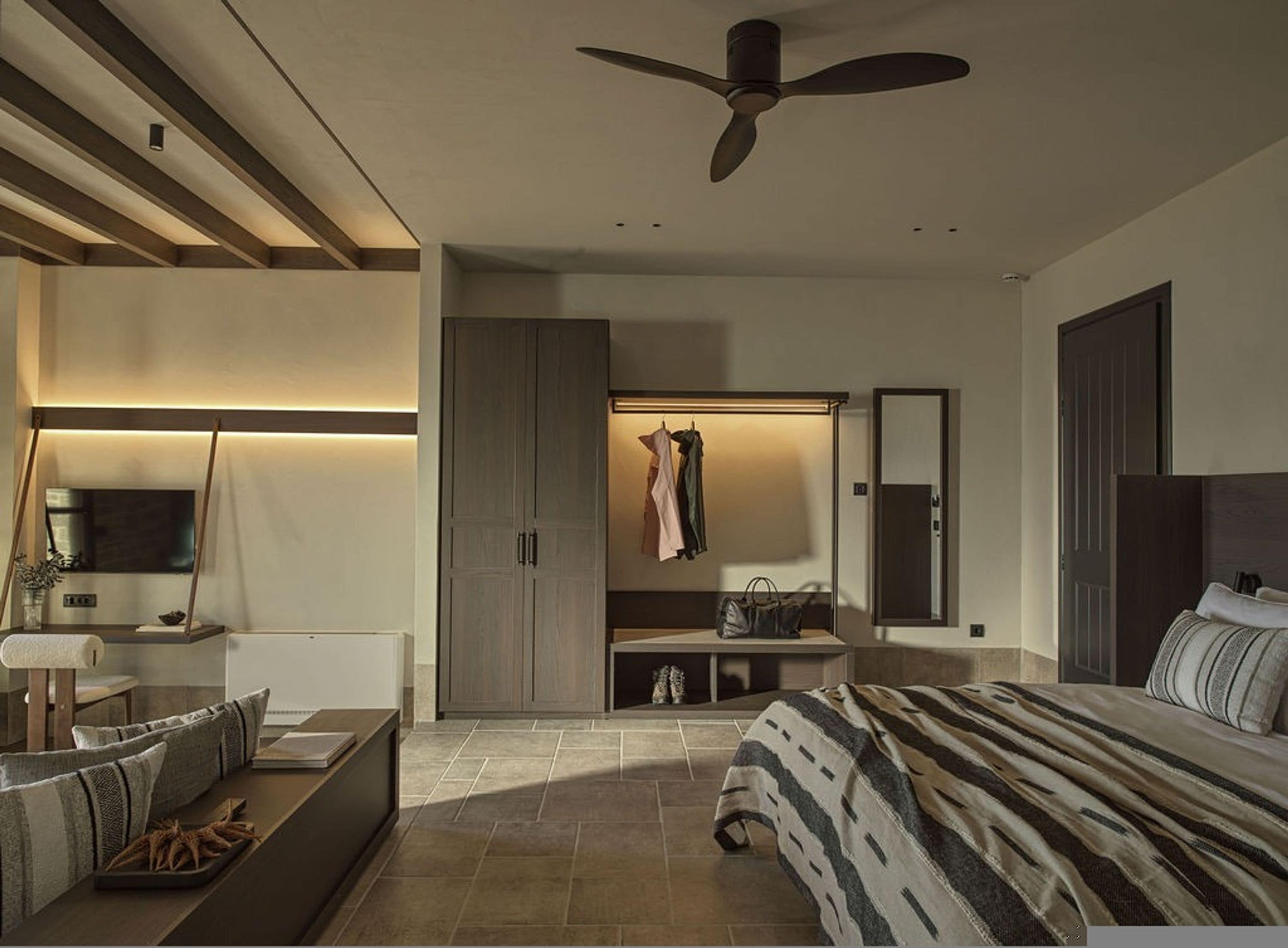 Un dormitorio moderno con cama, zona de estar, armario y ventilador de techo.