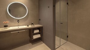 Een moderne badkamer met een ronde spiegel, een wastafel en een douchecabine van glas.
