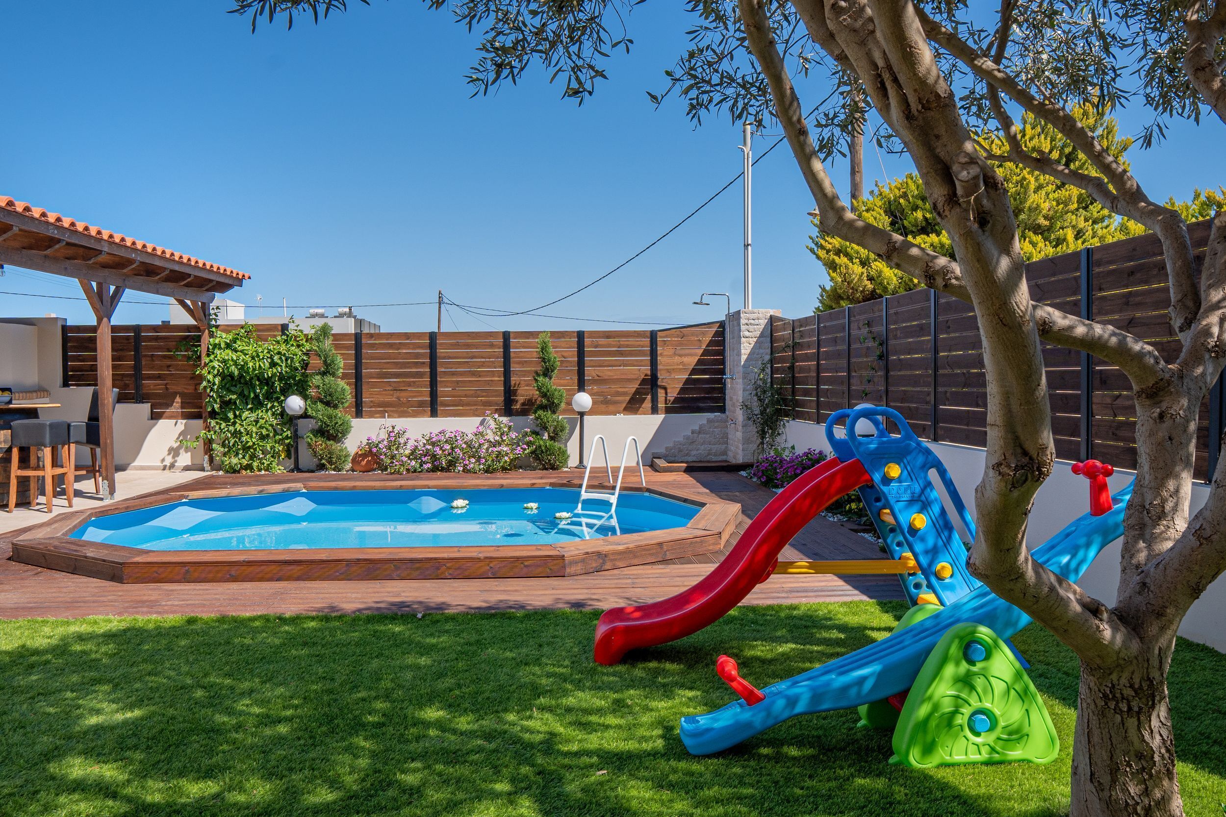 A backyard with a swimming pool, a slide, and a covered patio area.