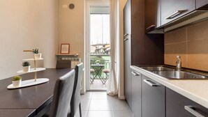 A compact kitchen with a sink, cabinets, and a dining area with a table and chairs. - Desenzano Suites - Achillea by Wonderful Italy (Desenzano del Garda)