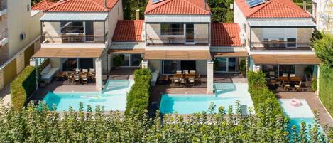 A modern villa with a swimming pool, multiple balconies, and solar panels on the roof.
