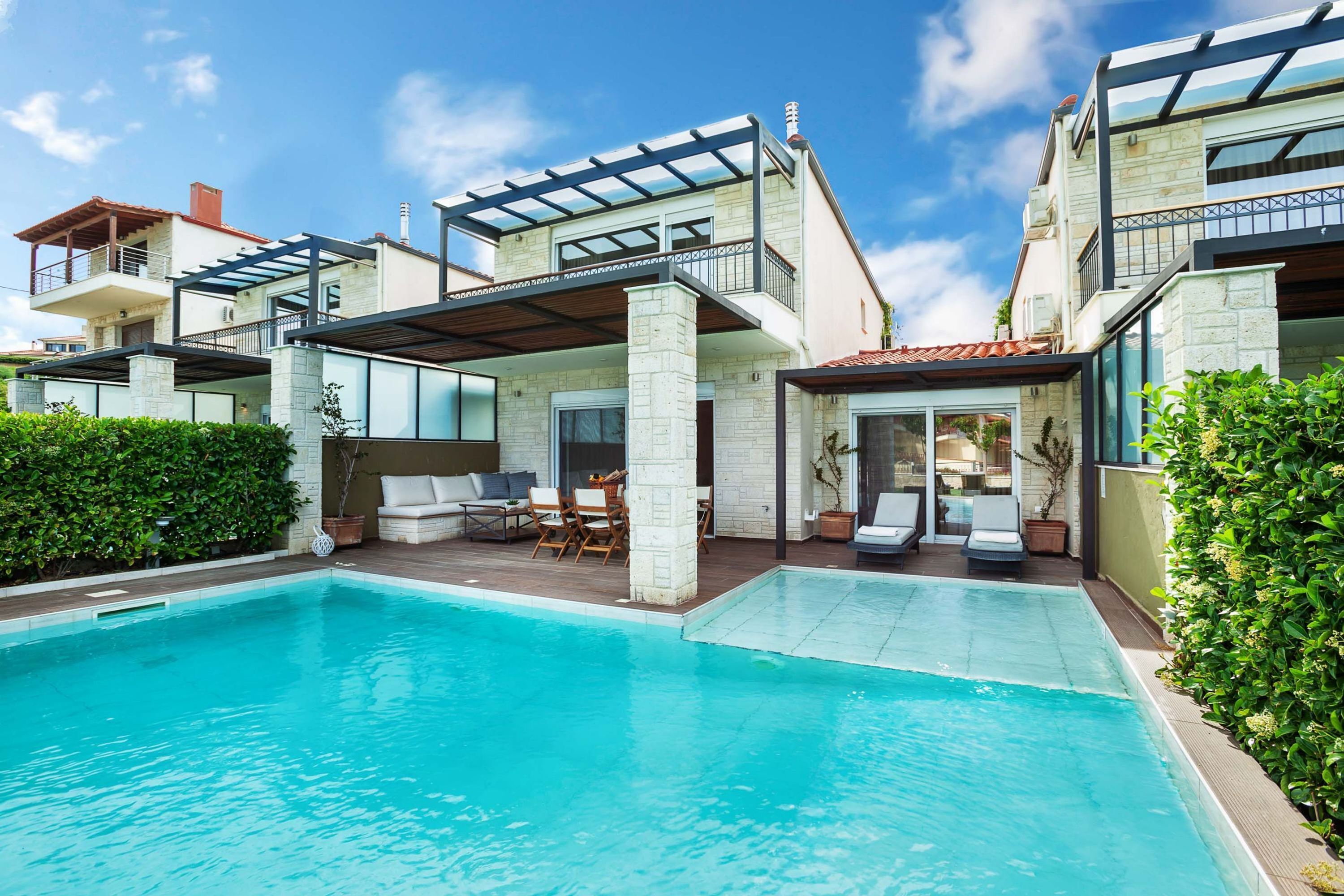 A modern two-story house with a swimming pool, outdoor seating, and a covered patio.