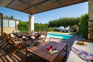 Eine Holzterrasse mit Pool, Gartenmöbeln und freiem Blick auf den Pool.