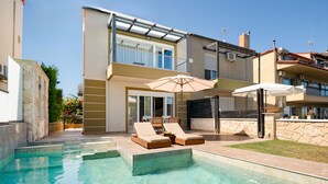 A modern two-story house with a swimming pool, outdoor seating, and a covered patio area. - Spa Villa Sunny in Chaniotis (Chaniotis)