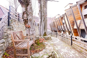 A wooden bench, stone walls, and a cobblestone path in a courtyard.
