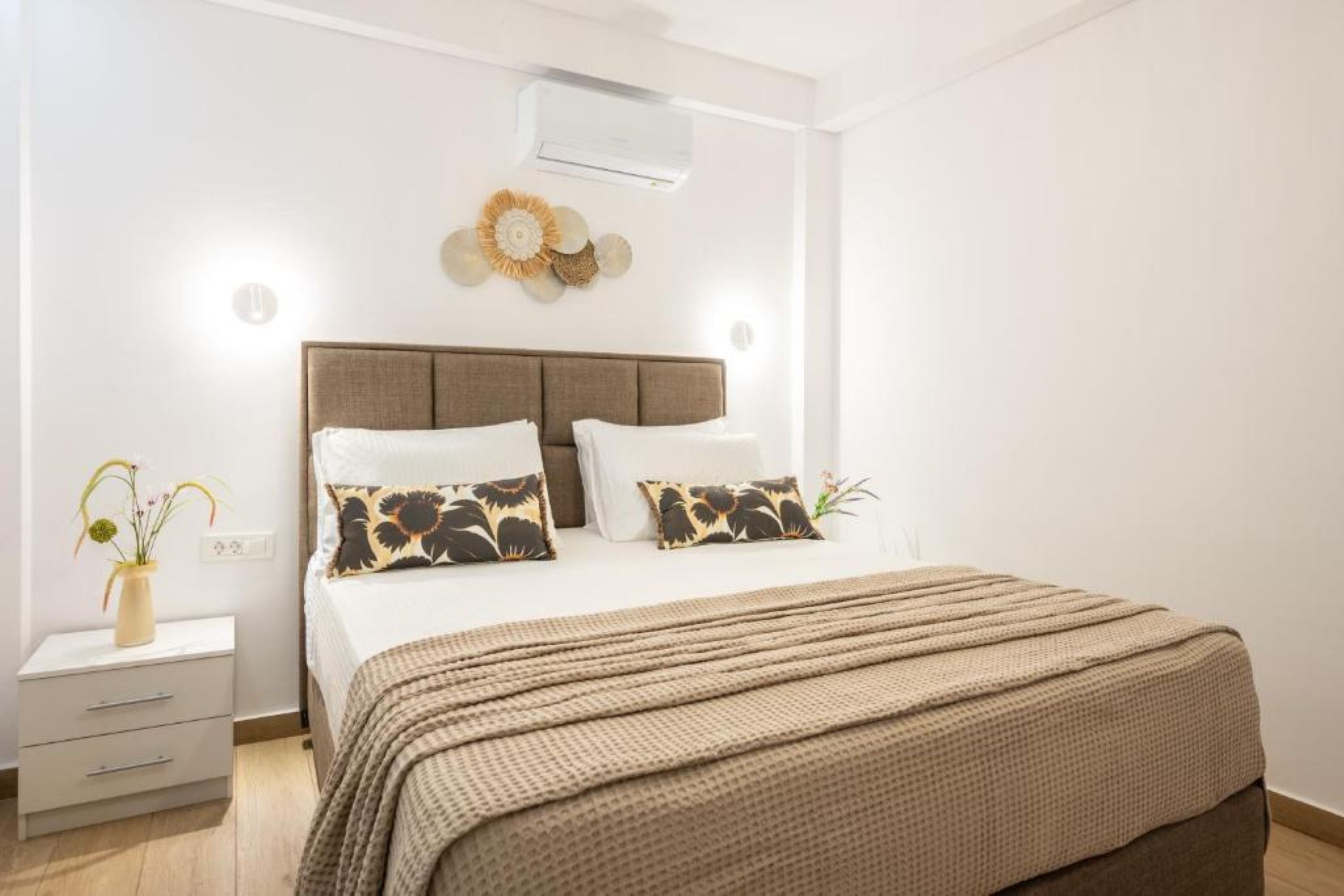 Ein Schlafzimmer mit einem Bett, Nachttischen, einer Wand-Klimaanlage und einem Wandbild.