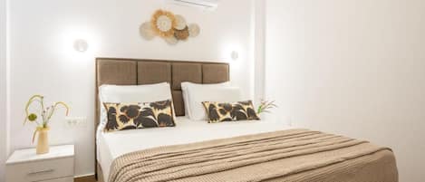 Ein Schlafzimmer mit einem Bett, Nachttischen, einer Wand-Klimaanlage und einem Wandbild.