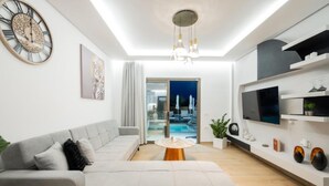A modern living room with a sofa, a coffee table, a TV, and a clock on the wall. - Villa Lux Stana II in Zakynthos (Laganas)
