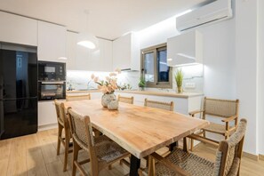 Eine moderne Küche mit einem Holztisch, Korbstühlen, einem eingebauten Ofen und einem Fenster mit Blick.