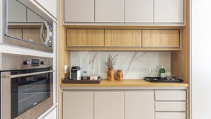 A compact kitchen with a built-in oven, a microwave, and a wooden countertop. - Apartamento Primavera (Rio de Janeiro)