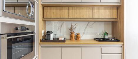 A compact kitchen with a built-in oven, a microwave, and a wooden countertop.