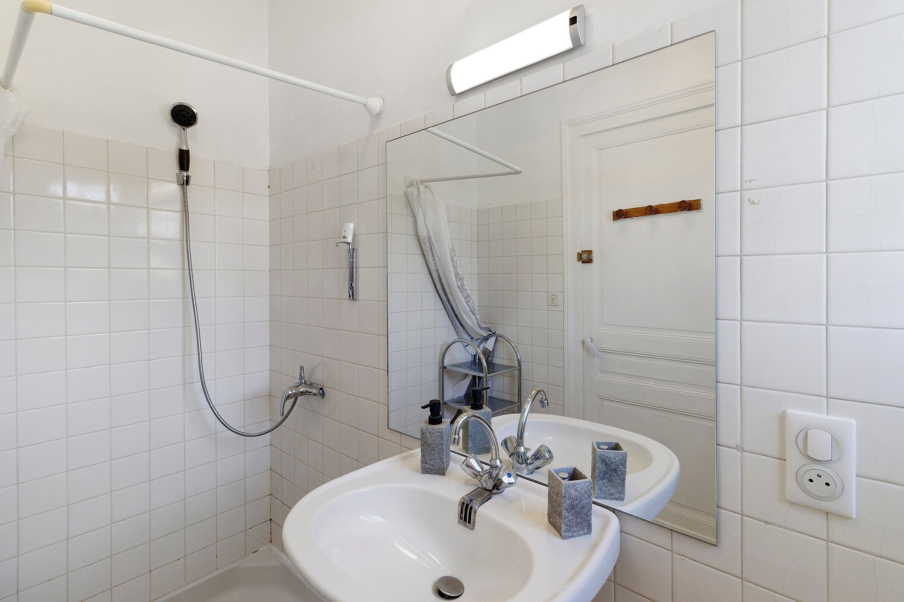 A bathroom with a shower, sink, mirror, and towel rack.