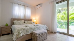 Een slaapkamer met een bed, nachtkastje en een rieten mand.
